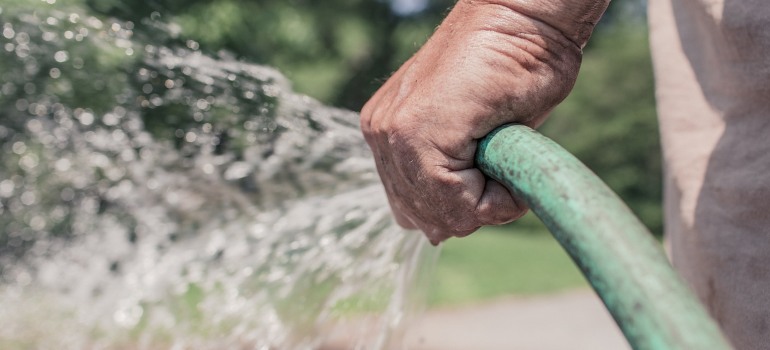 A person holding a garden hose.