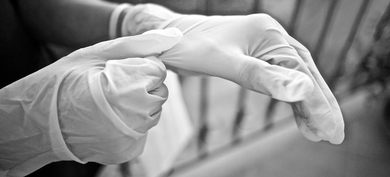 A person wearing gloves, which are a staple of bird mess cleanup guidelines.