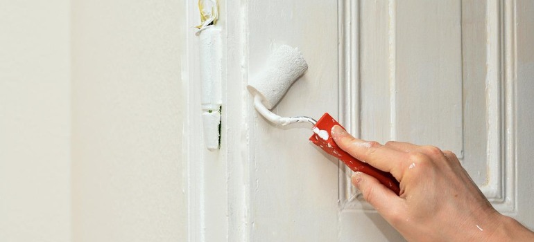 A person painting their doors white.