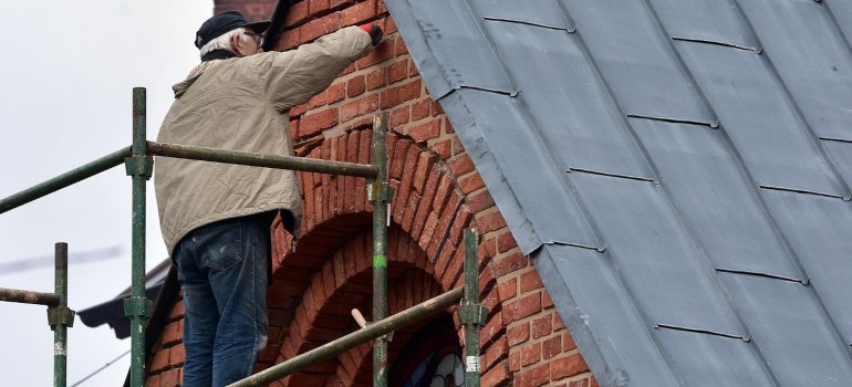 A man doing renovations on a roof after disregarding pressure washing.