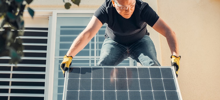 A man on the roof holding solar panel 