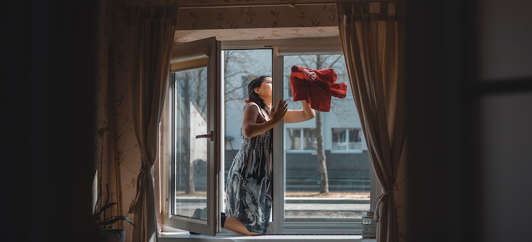 A woman cleaning a window as a way to keep your new Summerlin home clean