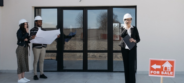 A couple looking at plans for a house and a woman on the phone representing selling a property with solar panels installed