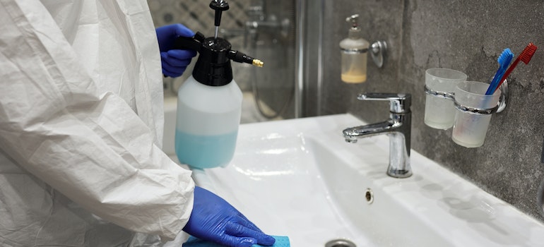 A person cleaning a sink in the bathroom